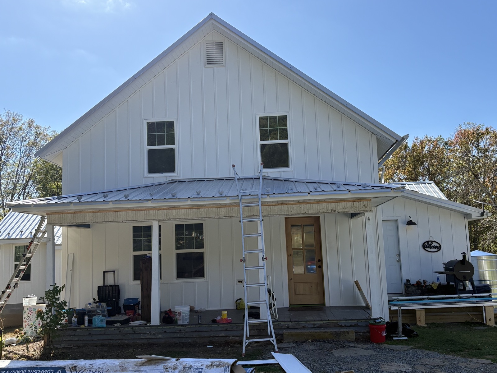 Two-story white board-and-batten farmhouse with standing-seam metal porch roof — completed exterior siding and trim project by Mountain State Home Innovations.